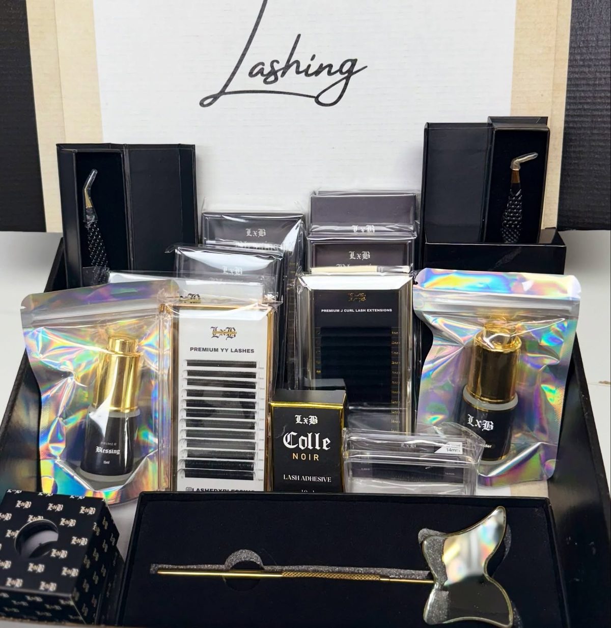 An LxB supply box: Colle Noir adhesive, Blessing primer, Premium YY lashes, J-curl trays and tweezers