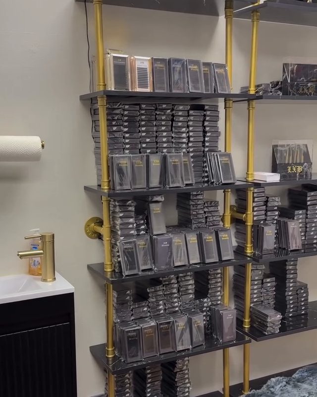 Gold shelving stocked with LxB lash trays in the studio
